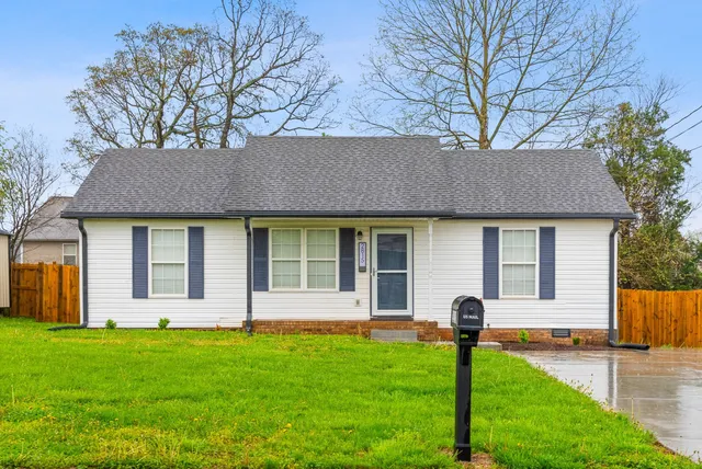 a front view of a house with yard and tree