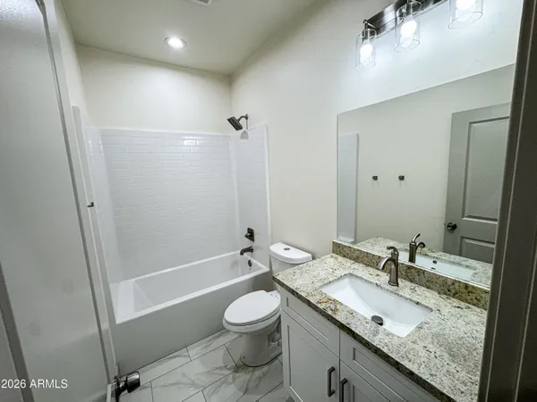 a bathroom with a granite countertop sink a toilet and shower