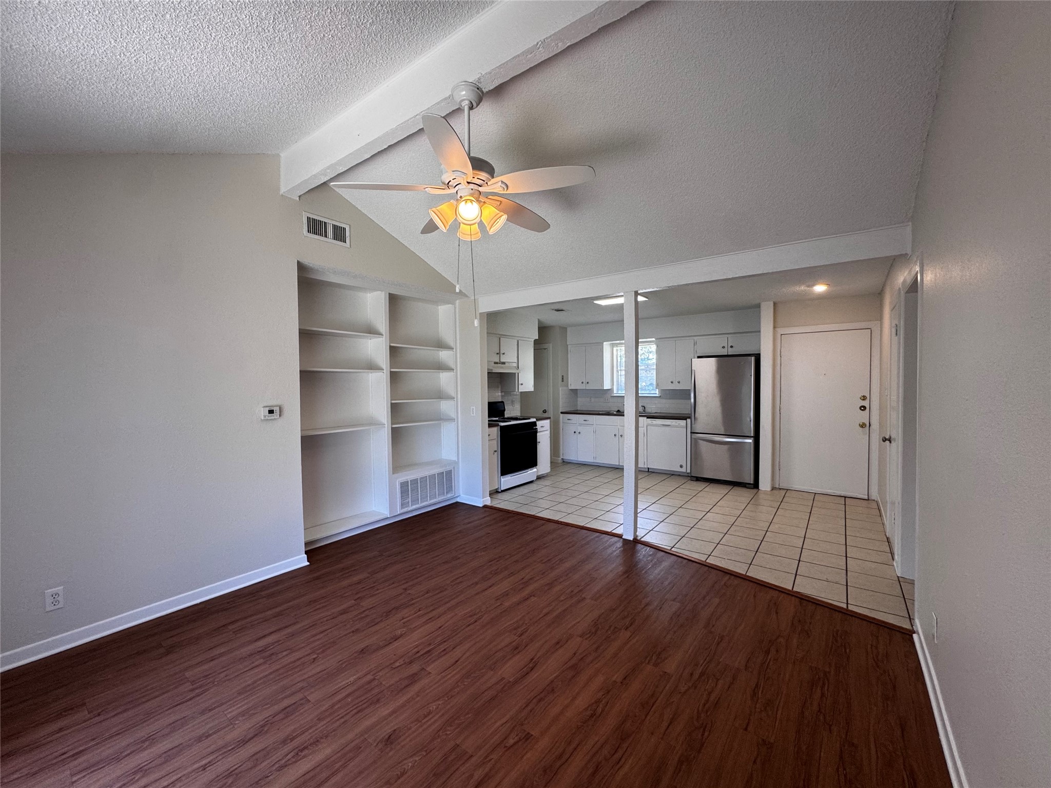 5916 A Cherry Loop Austin, TX 78745 - Photo 2 of 12 Built-in shelving and wood-like flooring define a versatile living space adjoining a tiled kitchen.