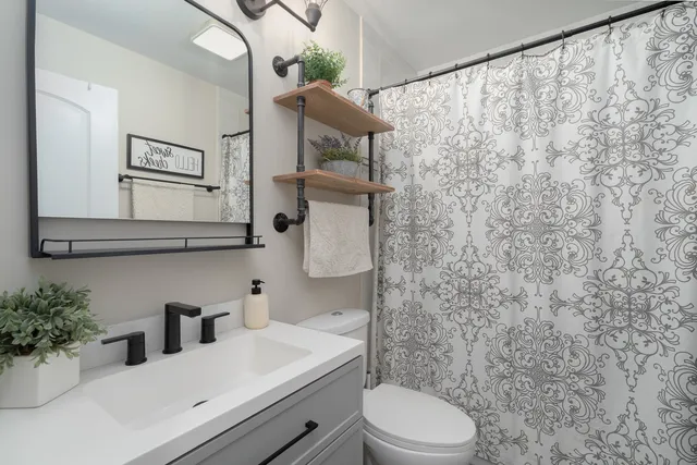 a bathroom with a sink a toilet and shower curtain