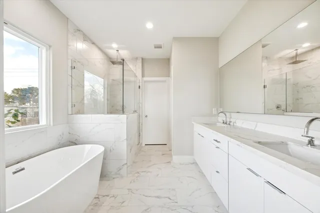 a bathroom with a tub a sink a mirror a shower and vanity