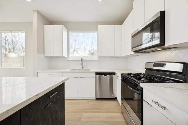 a kitchen with stainless steel appliances granite countertop white cabinets stove a sink and dishwasher