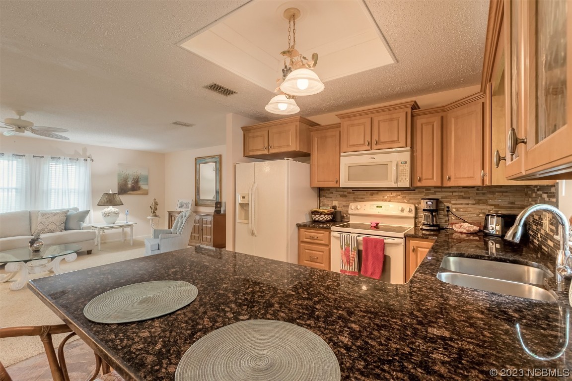 2828 Pine Tree Drive Edgewater, FL 32141 - Photo 12 of 38 a kitchen with stainless steel appliances granite countertop a stove a sink a refrigerator a dining table and chairs with white cabinets
