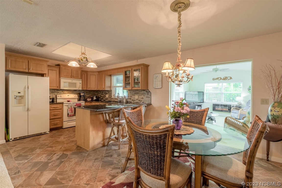 2828 Pine Tree Drive Edgewater, FL 32141 - Photo 13 of 38 a dining room filled chandelier and kitchen view