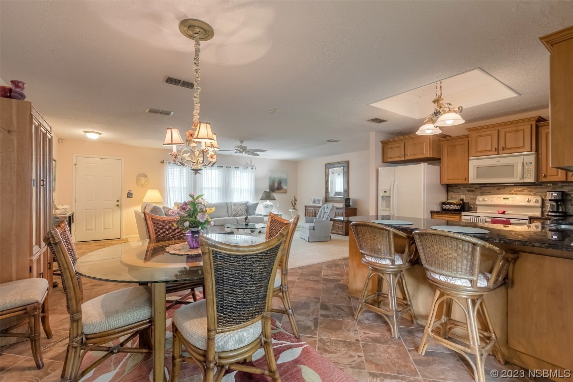 2828 Pine Tree Drive Edgewater, FL 32141 - Photo 14 of 38 a view of a dining room with furniture a kitchen and chandelier