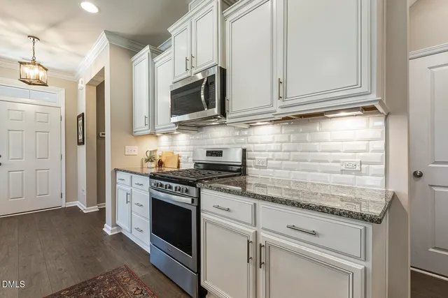 a kitchen with stainless steel appliances granite countertop white cabinets and a stove