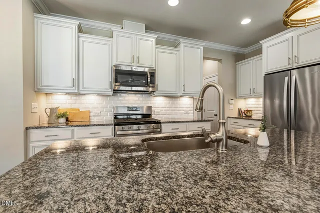 a kitchen with granite countertop a refrigerator and a stove top oven
