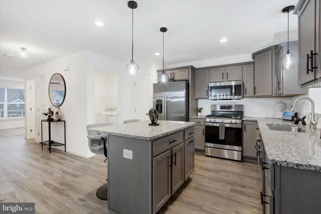 a kitchen with kitchen island granite countertop a sink appliances cabinets and a counter top space