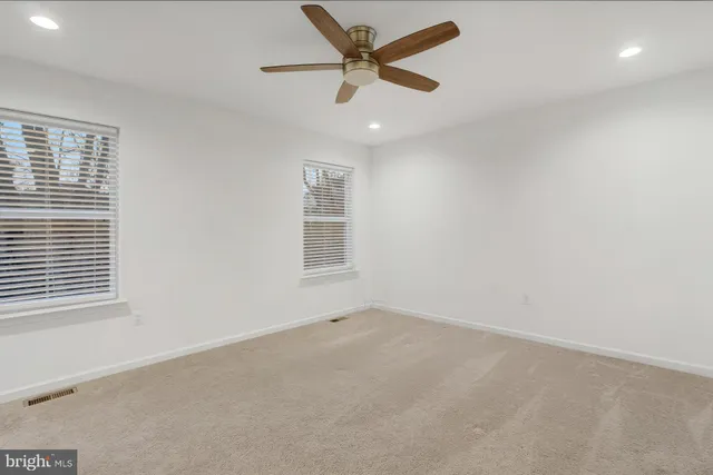 an empty room with a window and a ceiling fan
