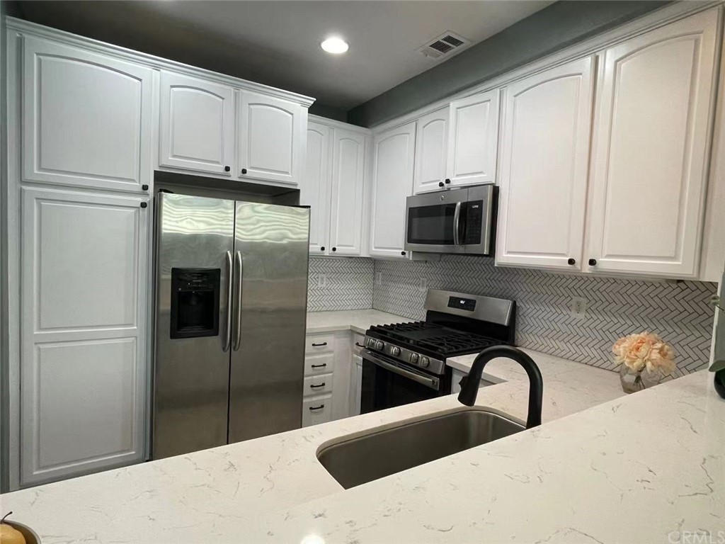21 Thorp Ladera Ranch Ladera Ranch, CA 92694 - Photo 14 of 15 a kitchen with stainless steel appliances granite countertop a refrigerator a stove a sink and white cabinets with a refrigerator