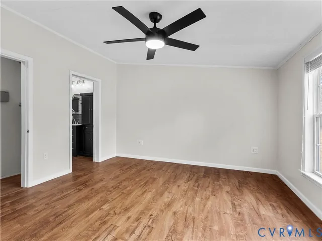 an empty room with wooden floor and a ceiling fan