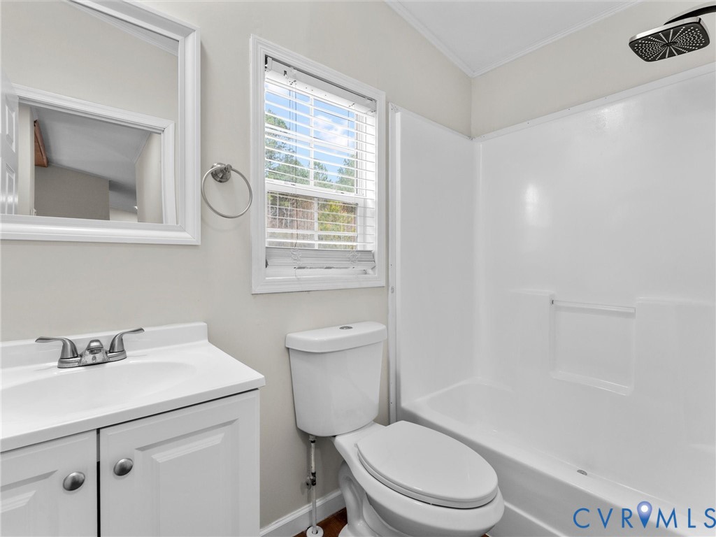 4772 Carsley Road Waverly, VA 23890 - Photo 21 of 38 a bathroom with a toilet a sink a mirror and a window