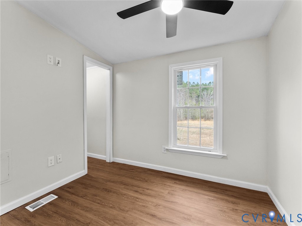 4772 Carsley Road Waverly, VA 23890 - Photo 22 of 38 an empty room with wooden floor chandelier fan and windows