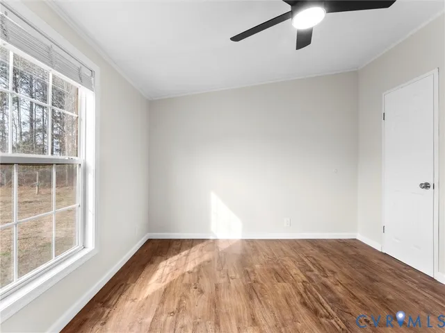 an empty room with wooden floor fan and windows