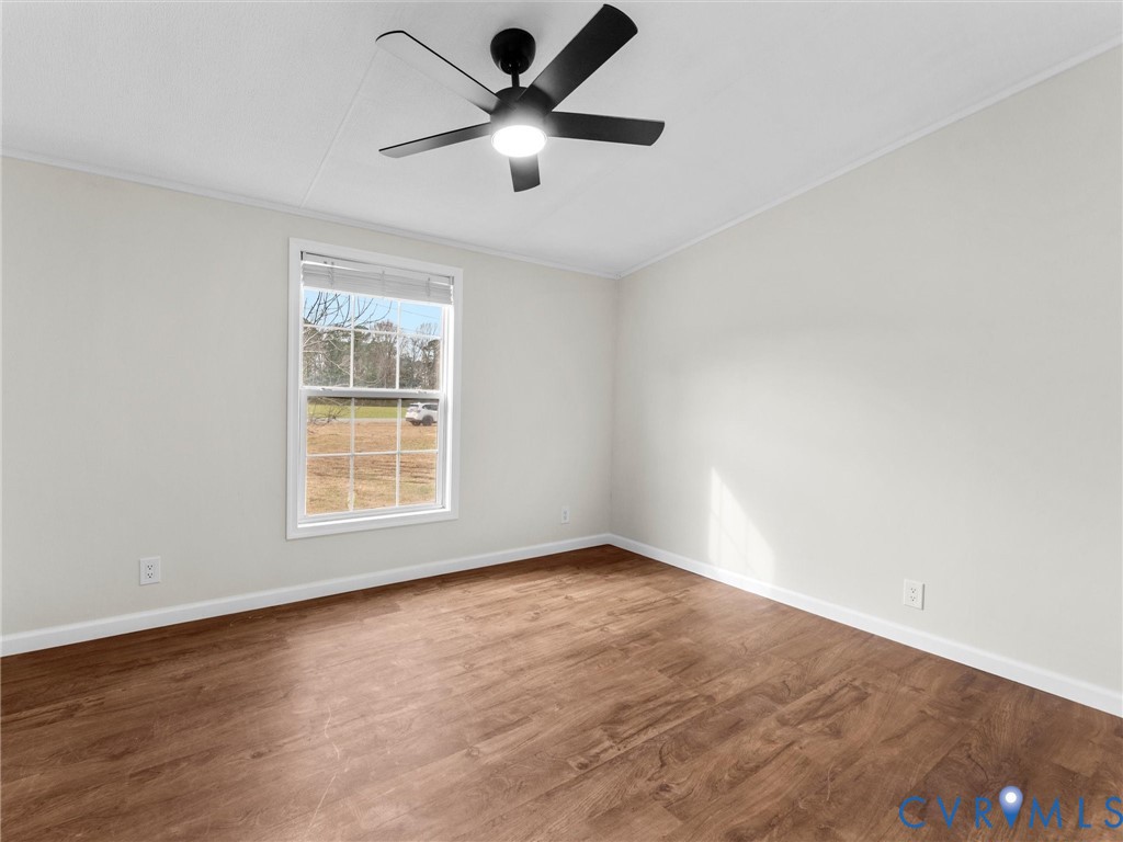 4772 Carsley Road Waverly, VA 23890 - Photo 28 of 38 an empty room with wooden floor fan and windows
