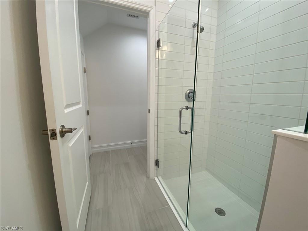 7530 Rockefeller Drive Naples, FL 34119 - Photo 10 of 18 Modern bathroom featuring a frameless glass shower enclosure, white subway tile shower surround, and a chrome shower fixture
