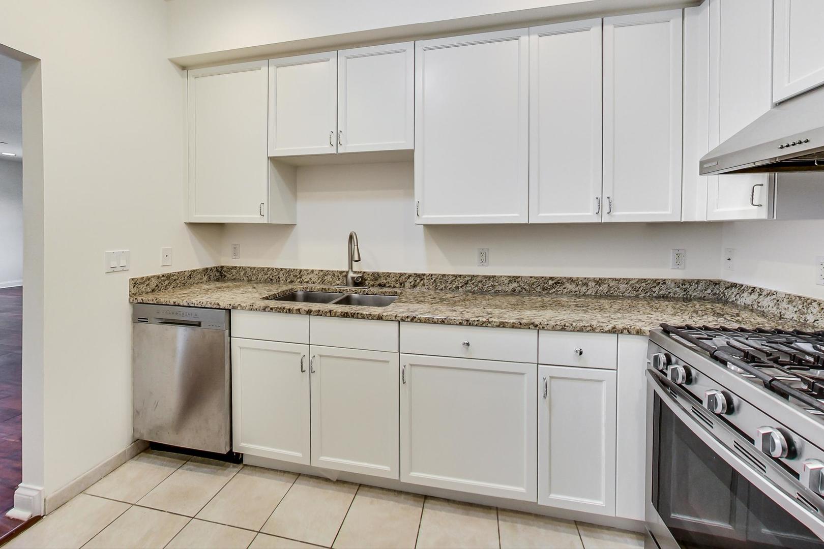 720 Green Bay Road, Unit 2D Winnetka, IL 60093 - Photo 9 of 41 a kitchen with granite countertop white cabinets and stainless steel appliances