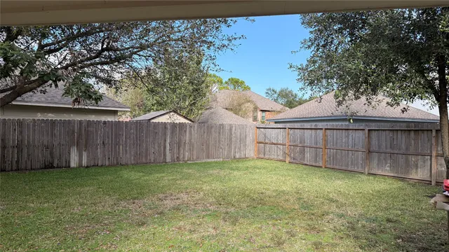 a view of a backyard with a tree and wooden fence