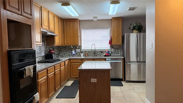a kitchen with refrigerator a microwave a sink and cabinets