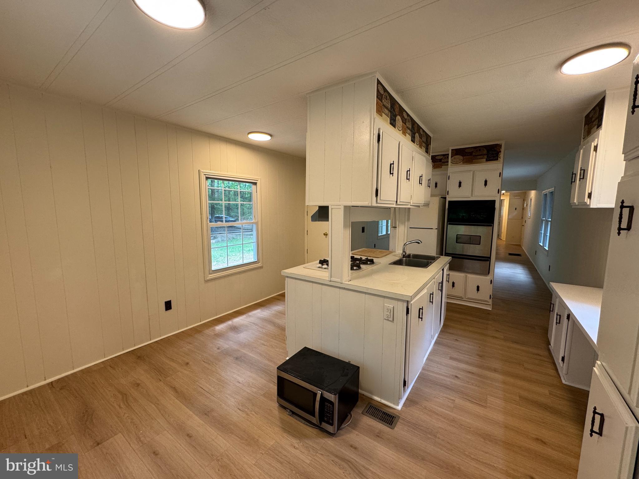 9216 Lawyers Road Spotsylvania, VA 22551 - Photo 7 of 19 a kitchen with stainless steel appliances a stove top oven a sink a refrigerator white cabinets and wooden floor