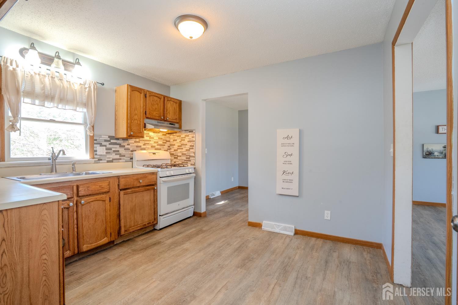 1834 Holly Road North Brunswick, NJ 08902 - Photo 11 of 26 a kitchen with granite countertop a stove a sink and a window