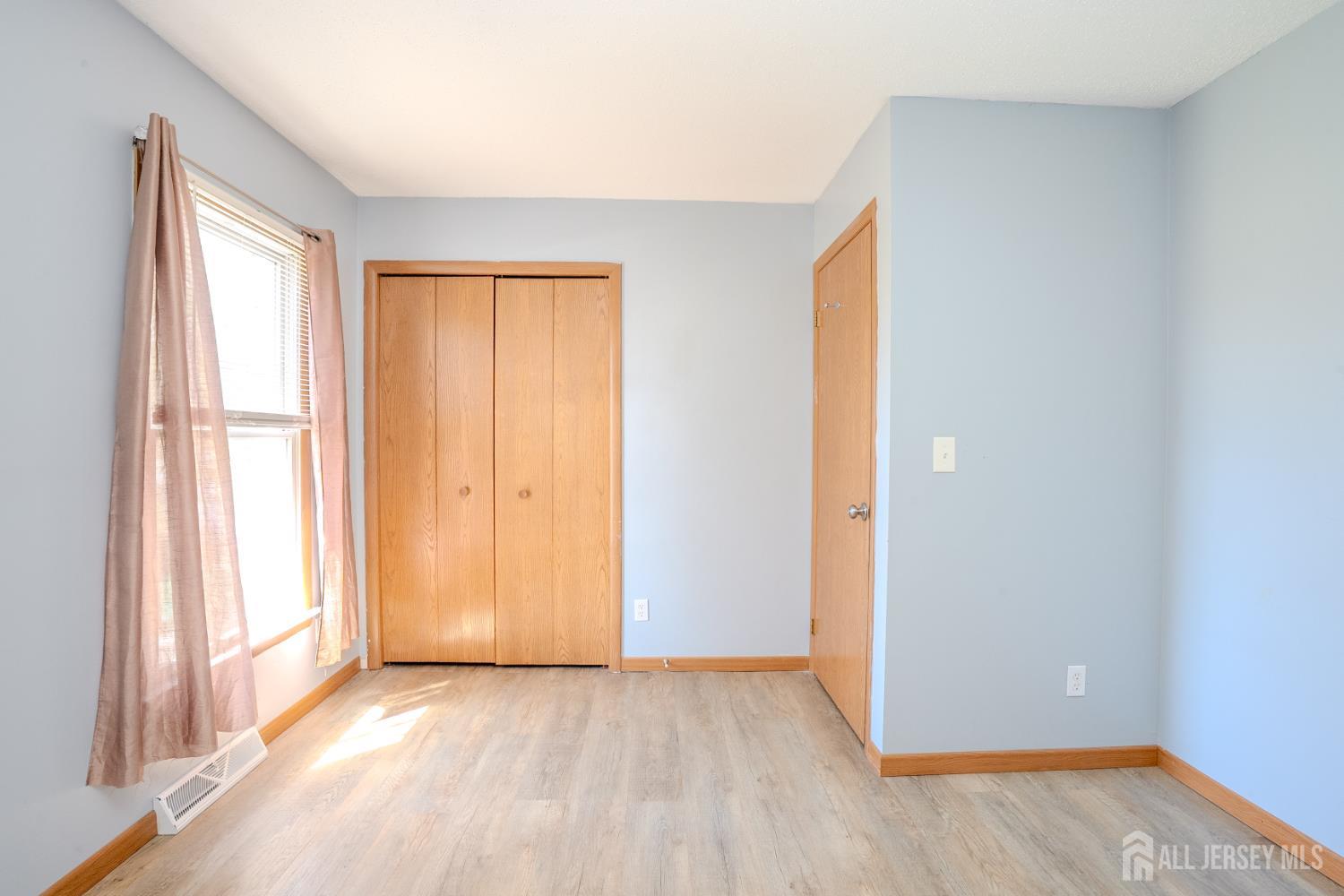 1834 Holly Road North Brunswick, NJ 08902 - Photo 16 of 26 a view of an empty room with wooden floor and a window