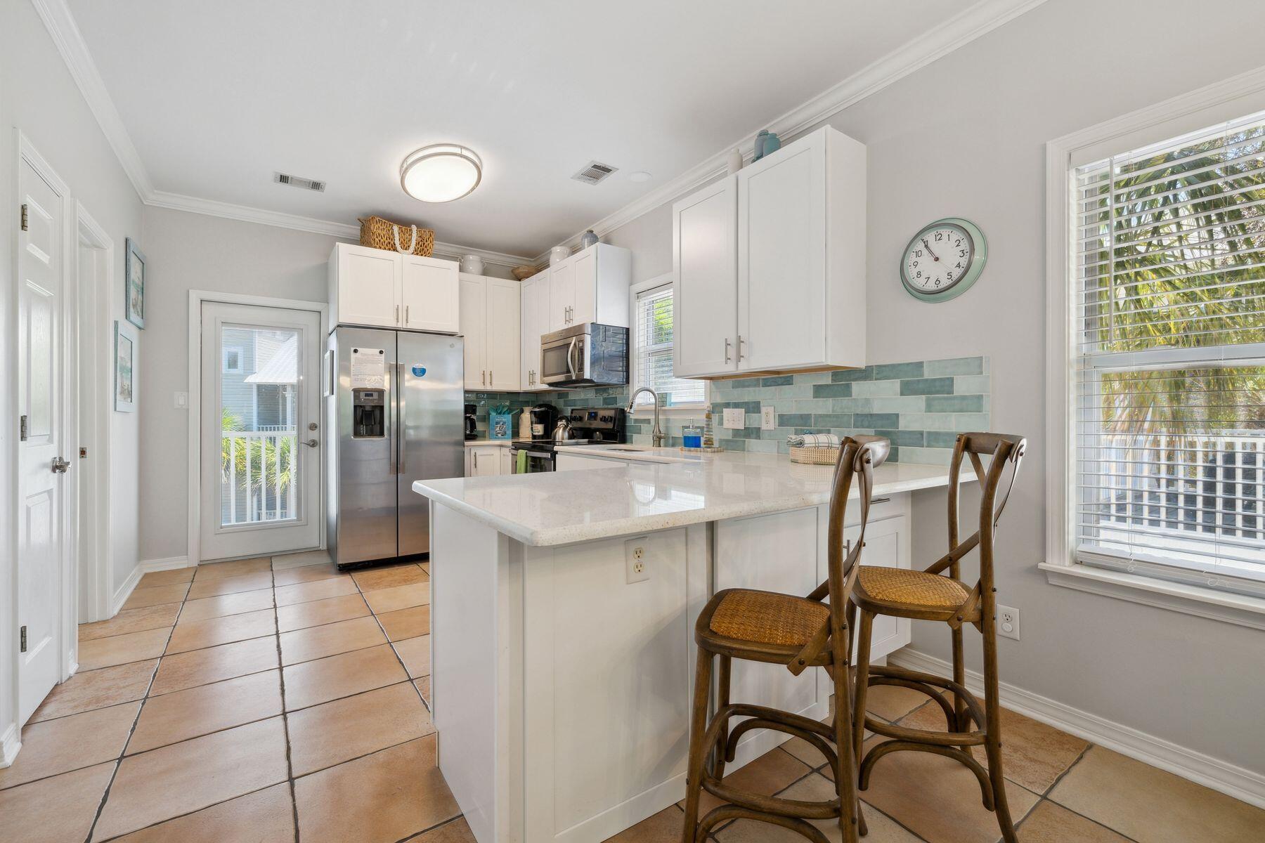 104 Emerald Dunes Circle Santa Rosa Beach, FL 32459 - Photo 12 of 53 a kitchen with stainless steel appliances granite countertop a stove a refrigerator a microwave oven and a dining table with wooden cabinet