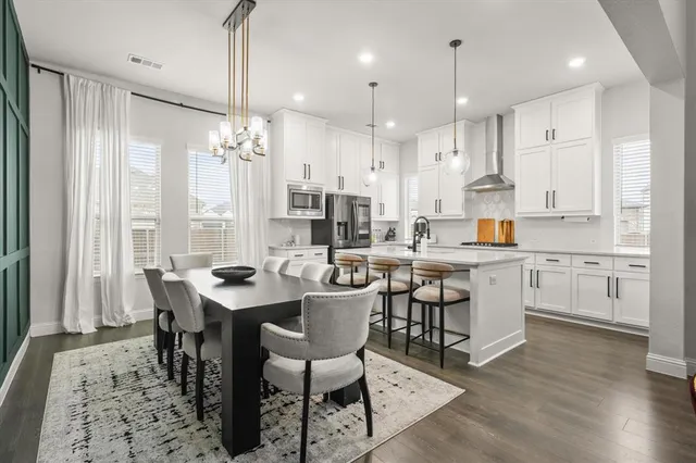 a open dining room with stainless steel appliances kitchen island granite countertop a table chairs and a refrigerator
