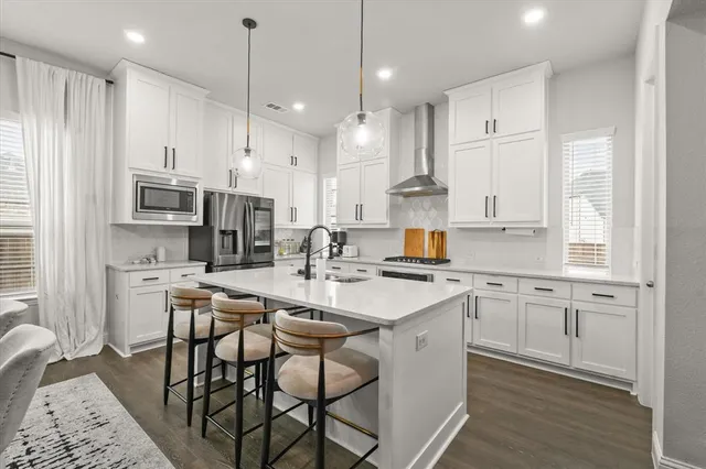 a kitchen that has a lot of cabinets in it with stainless steel appliances granite countertop a dining table and chairs a oven with wooden floors