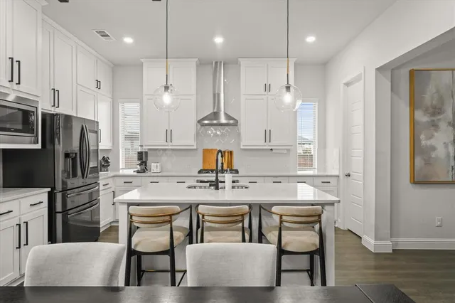 a kitchen with kitchen island granite countertop a table chairs refrigerator and microwave