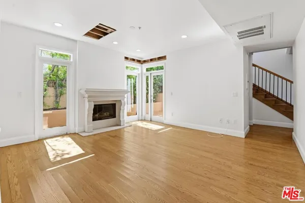 a view of an empty room with wooden floor fireplace and a window