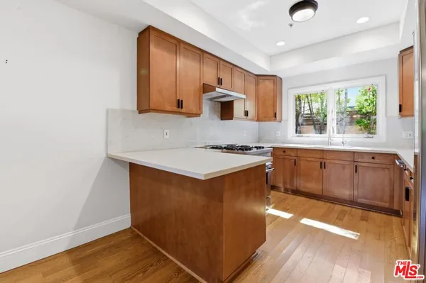 a kitchen with stainless steel appliances granite countertop a sink a stove a refrigerator cabinets and wooden floor
