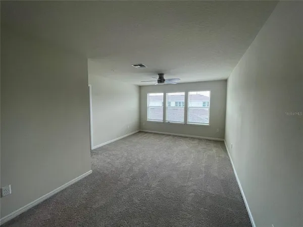 an empty room with a ceiling fan and window