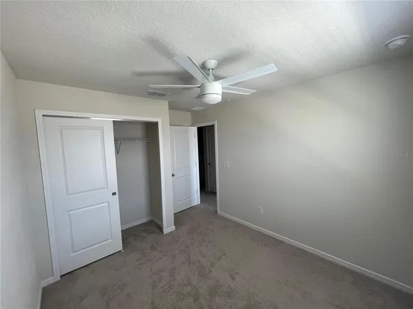an empty room with closet and a chandelier fan