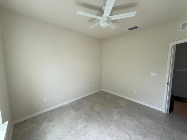an empty room with a ceiling fan and carpet