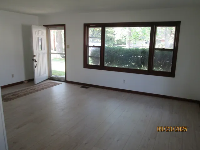 an empty room with wooden floor and windows