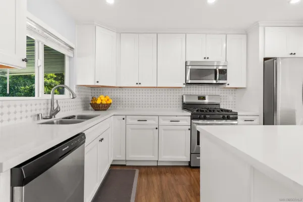 a kitchen with stainless steel appliances a stove a sink a refrigerator a window and cabinets
