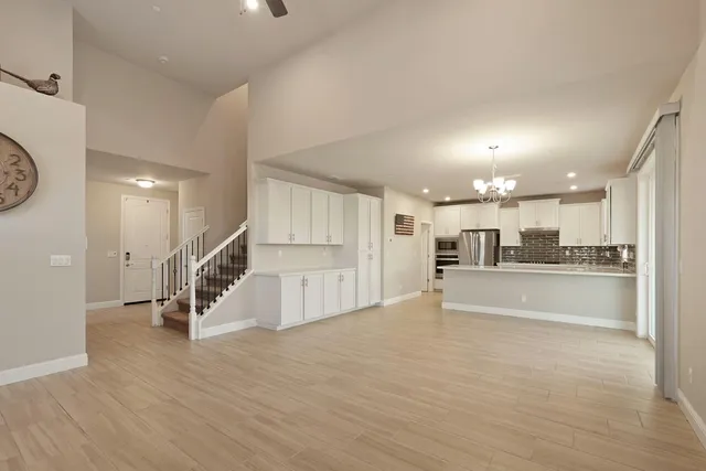 a large white kitchen with kitchen island a sink a center island stainless steel appliances and a refrigerator