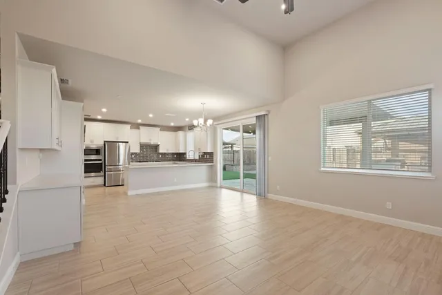 a kitchen with granite countertop a refrigerator a sink and white cabinets