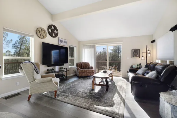a living room with furniture floor to ceiling window hardwood floor and a flat screen tv