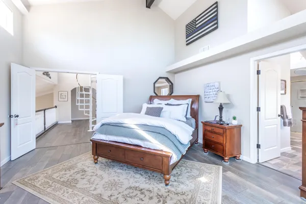 a spacious bedroom with a bed and wooden floor