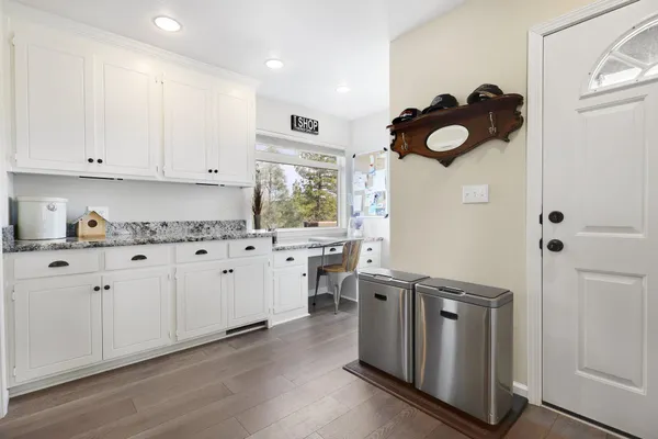 a kitchen with stainless steel appliances granite countertop a sink dishwasher stove and white cabinets with wooden floor