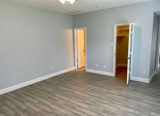 a view of an empty room with wooden floor and a window