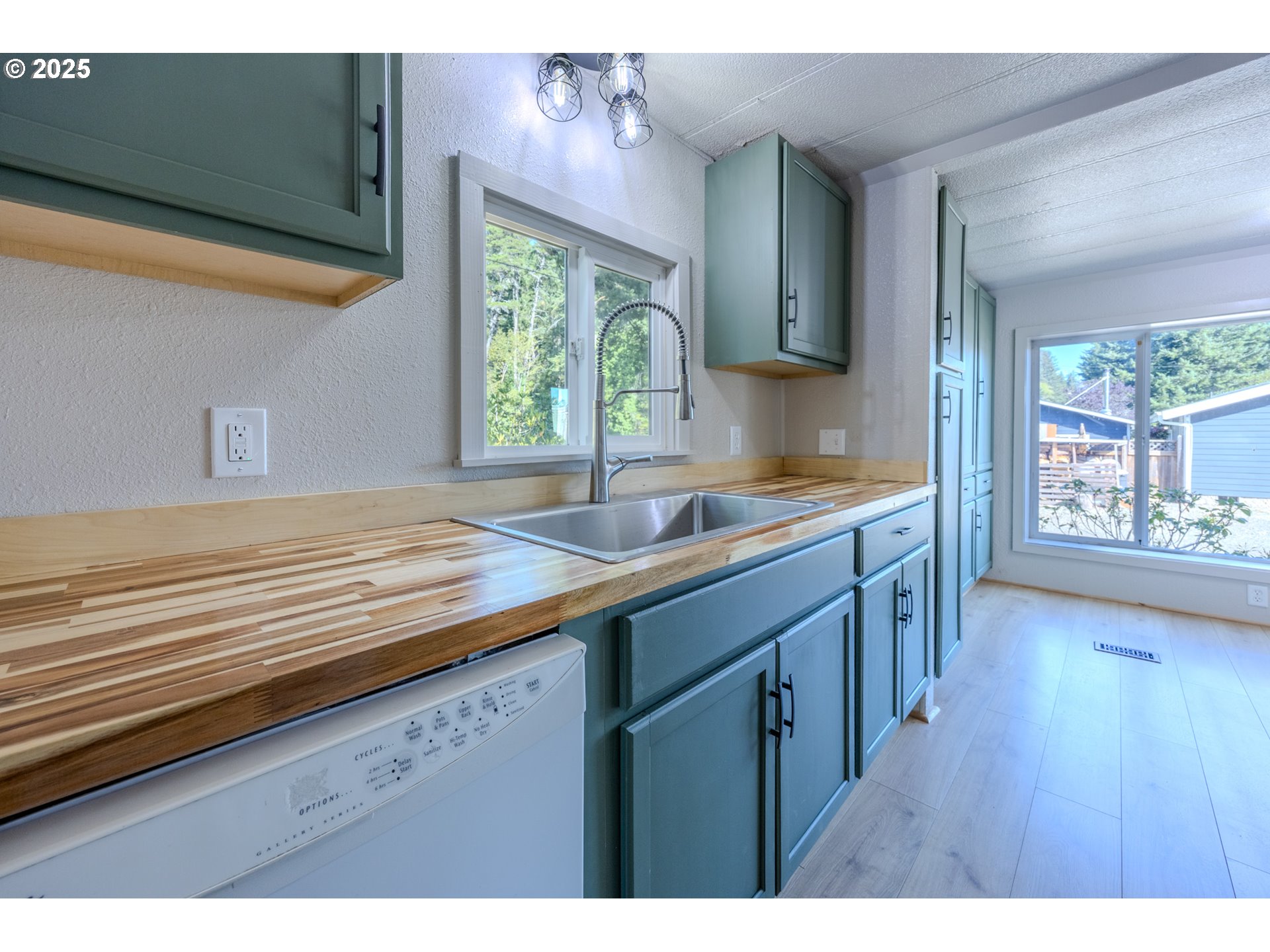 83763 Highway 101, Unit 21 Florence, OR 97439 - Photo 8 of 36 a kitchen with kitchen island wooden floors wooden cabinets a sink a window and appliances