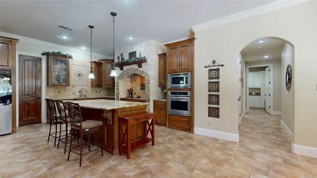 a kitchen with stainless steel appliances kitchen island granite countertop a table and chairs in it
