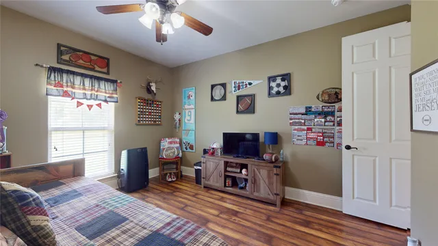 a bedroom with furniture a flat screen tv and a window