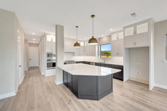 a large kitchen with stainless steel appliances kitchen island a stove a sink a refrigerator and a wooden floor