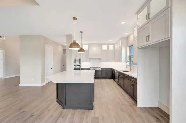 a large kitchen with stainless steel appliances a large counter top a sink a refrigerator and a cabinets