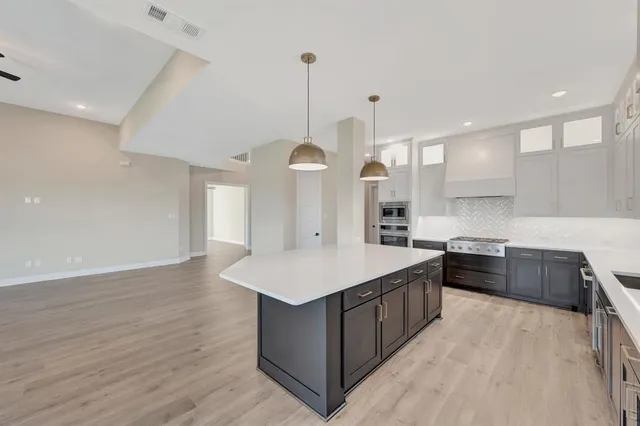 a kitchen with stainless steel appliances granite countertop a sink a counter space and wooden floor