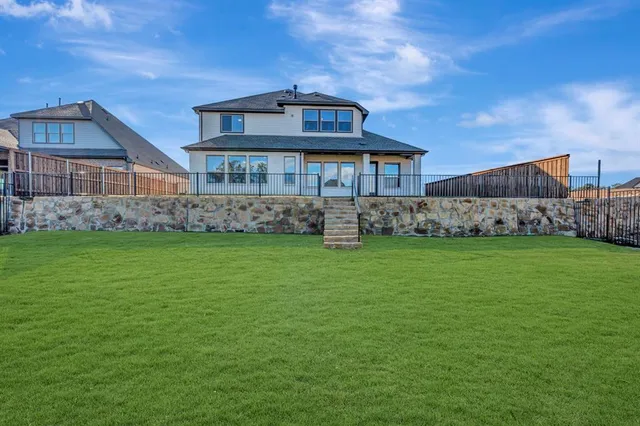 a view of a big house with a big yard plants and large trees